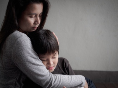 Sad little boy being hugged by his mother at home. Parenthood, Love and togetherness concept.